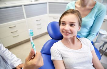 a girl in a dental chair being educated about proper brushing