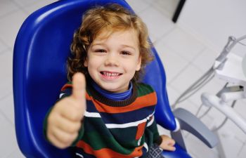 Smiling boy showing his thumb up at a pediatric dentistry office.