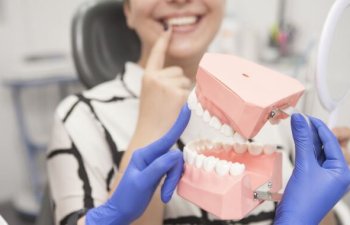 Dentist explaining dental implants to a female patient sitting in a dental chair.